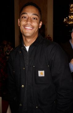 a smiling man wearing a black jacket and white shirt