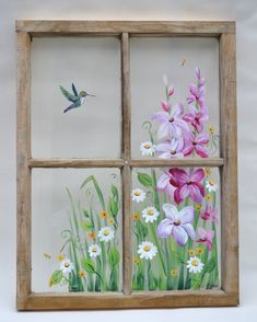 a window with flowers painted on it and a hummingbird flying over the windowsill