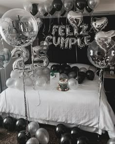 a bed topped with lots of silver and black balloons