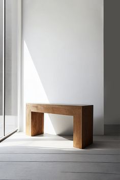 a wooden bench sitting on top of a white floor next to a glass door in a room