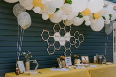 a table with balloons and pictures on it in front of a blue wall at a party