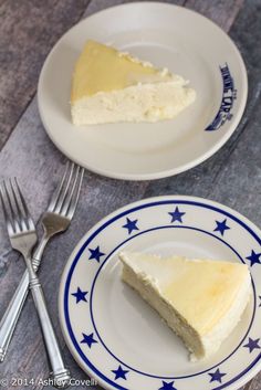 two plates with slices of cheesecake on them next to silverware and forks,