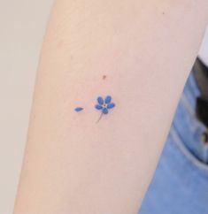 a small blue flower tattoo on the arm