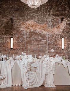 the table is set up with white flowers and cloth draped over it, along with candles