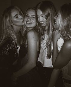 four beautiful young women standing next to each other in a black and white photo with their mouths open