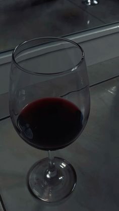 a glass of red wine sitting on top of a counter