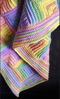 a multicolored crocheted blanket sitting on top of a black surface