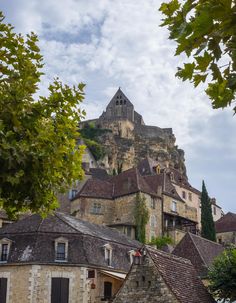 an old castle is on top of a hill in the distance, surrounded by trees and buildings