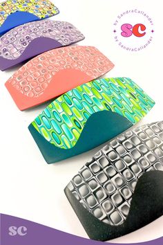 four different colored pieces of plastic sitting on top of a white table with purple and green designs