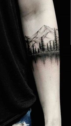 a man's arm with a mountain and pine trees tattoo on the left forearm