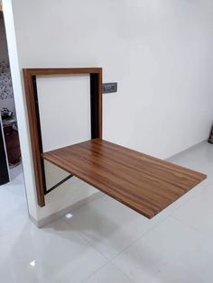 a wooden shelf sitting on top of a white floor next to a wall mounted mirror