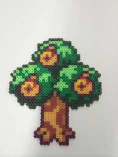 a cross - stitch tree is shown on a white surface with green leaves and flowers