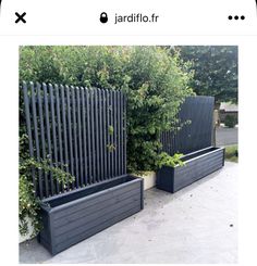 two black planters sitting next to each other in front of a fenced area