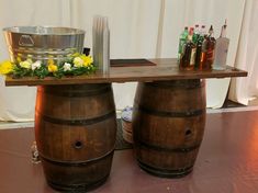 two wooden barrels sitting next to each other on top of a table covered in bottles