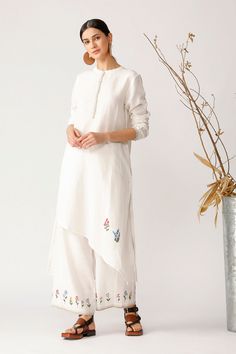 Editor's Note High Low Asymmetric Placket Tunic And Pant With Embroidery At The Bottom Color: Beige Fabric: Linen Care: Dry Clean Only About the Designer Payal Pratap’ for the Indian woman who is modern, independent, yet deeply rooted in tradition at the same time. The Brand believes in timeless elegance, rustic exuberant creations, and is craft-based, adorning the rich cultural heritage which does not follow a fashion trend in particular. The ethos of the Brand lies in texturing, patchwork, and Spring Kurta With Embroidered Hem And Long Sleeves, Spring Long Sleeve Kurta With Embroidered Hem, White Asymmetrical Hem Tunic For Spring, Payal Pratap, Tunic With Pants, Asymmetric Tunic, High Low Tunic, Embroidered Pants, Indian Woman