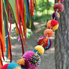 colorful pom - poms are hanging from a tree