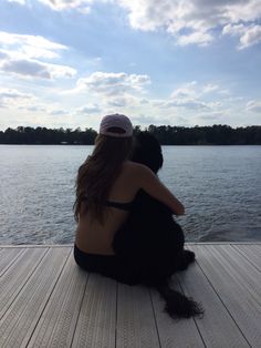 two people sitting on a dock looking out at the water