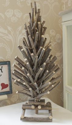 a small wooden christmas tree sitting on top of a table next to a framed picture