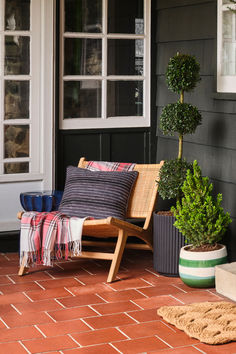 a wooden chair sitting on top of a brick floor next to a potted plant