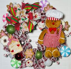 a wreath with a teddy bear on it and christmas decorations around the wreath is shown