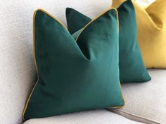 two green and yellow pillows sitting on top of a white couch next to each other