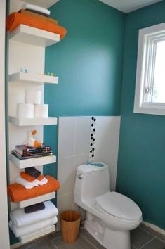 a white toilet sitting next to a window in a bathroom under blue and orange walls