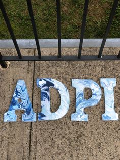 the word appla spelled in marbled letters on a sidewalk next to a fence