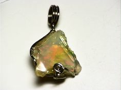 This pendant features a raw, uncut Ethiopian opal. The stone weighs in at 6.5 carats, and measures 0.65 x 0.66 inches (16.6 x 16.8 mm) Ethiopian hydrophane opal is really exciting material. Since its discovery in 2008, it has provided very stable and beautiful stones with such rich and varied color as to rival the best of Australia. Ranging from black to white, with fire spanning the entire rainbow, just about every taste is catered to by this find. This is a really beautiful piece. It has a lig Unique Raw Jewelry For Wedding, Unique Raw Jewelry For Weddings, Unique Raw Jewelry For Gifts, Ethiopian Opal Jewelry With Natural Stones As Gift, Elegant Raw Jewelry Gift, Elegant Raw Jewelry For Gifts, Fusion Style Opal Jewelry For Gifts, Unique Ethiopian Opal Gemstone Jewelry, Fusion Style Opal Jewelry Gift