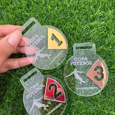 three different colored tags in the grass with one being held by someone's hand