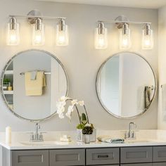 two bathroom sinks with mirrors and lights above them