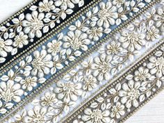 three different types of embroidered fabric on a white tablecloth with gold trimmings