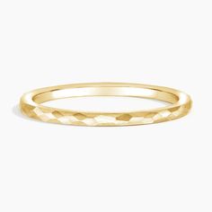 a yellow gold wedding band that is made out of thin, textured material and has a diamond cut design on the side