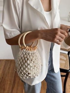 a woman holding a white purse on top of a wooden floor