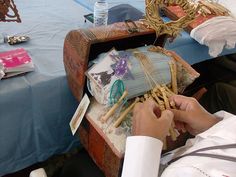 a person sitting at a table working on some kind of crafting project with sticks