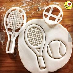 two tennis racquets and a ball on a wooden table with plastic cutters