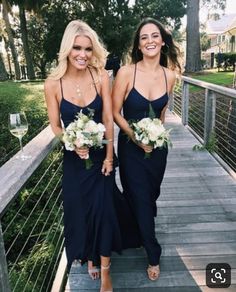 two beautiful women standing on a wooden bridge holding bouquets and smiling at the camera