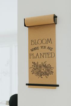 a sign hanging on the wall that says bloom where you are planted