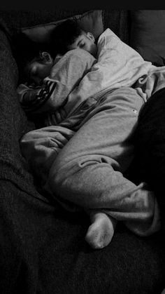 a man sleeping on top of a couch next to a woman in a black shirt