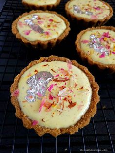 four small desserts sitting on top of a cooling rack with toppings in them