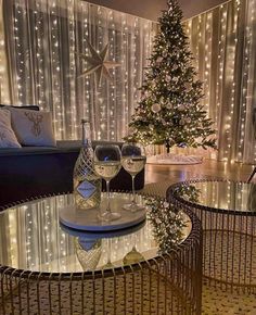 a living room with a christmas tree and two wine glasses on the glass coffee table