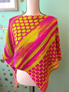 a pink and yellow knitted shawl on a mannequin