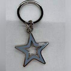 a silver and blue star shaped keychain on a white surface with a black ring