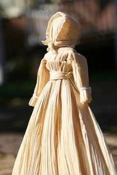 a doll in a long dress is standing on the ground with her head turned to the side