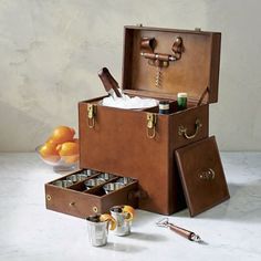 an open suitcase sitting on top of a table next to oranges and other items