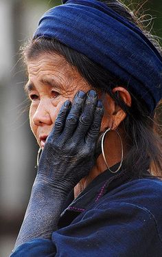 an old woman wearing black gloves and holding her hands up to her face while talking on the phone