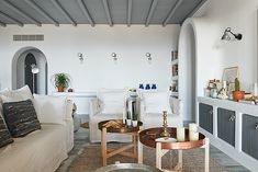 a living room filled with white furniture and lots of pillows on top of it's walls