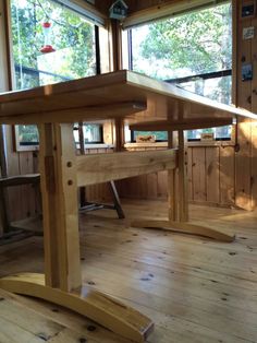 a wooden table sitting on top of a hard wood floor next to a large window