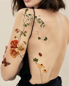 the back of a woman's body with flowers and butterflies painted on her arm