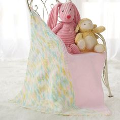 two stuffed animals sitting on top of a white bed with a pink blanket and pillow