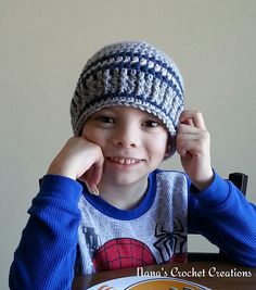 a young boy sitting at a table wearing a crocheted hat